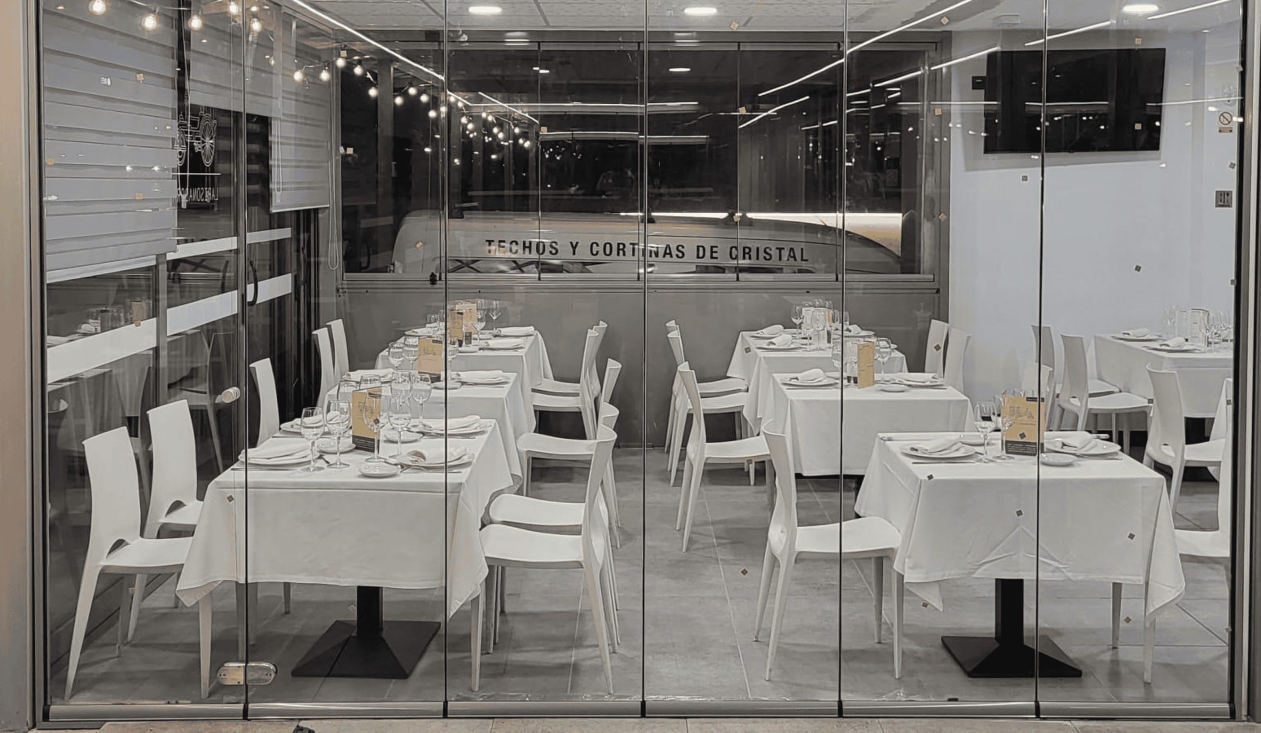 Restaurante con mesas tras cristalera de cerramiento