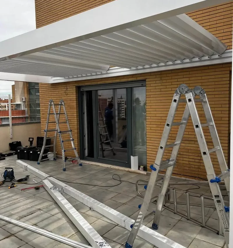 pergola bioclimatica en entrada en madrid con escaleras y equipo de montaje